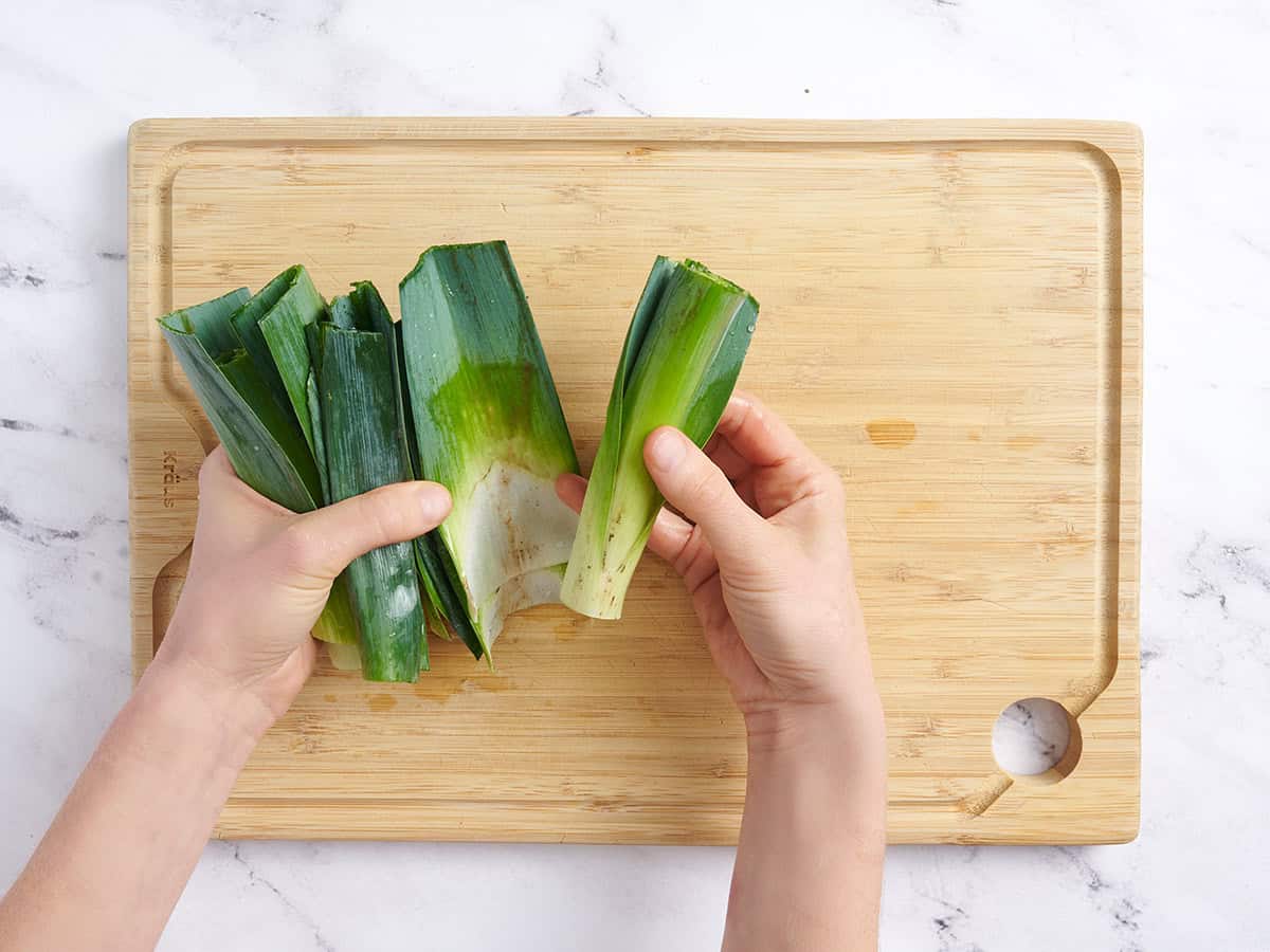 Hands separating leek leaves to wash them.