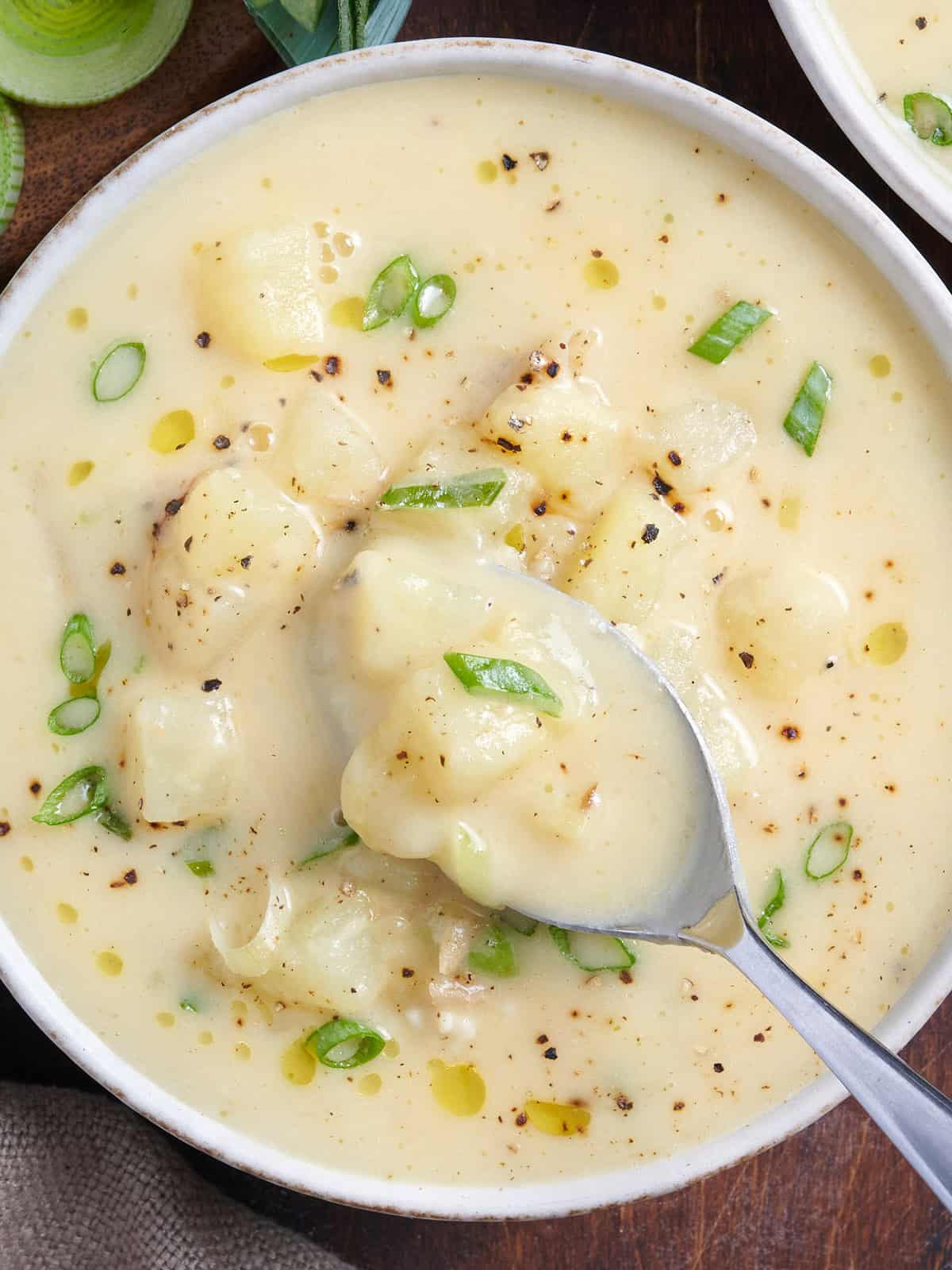 Overhead view of potato leek soup in a bowl with a spoon.