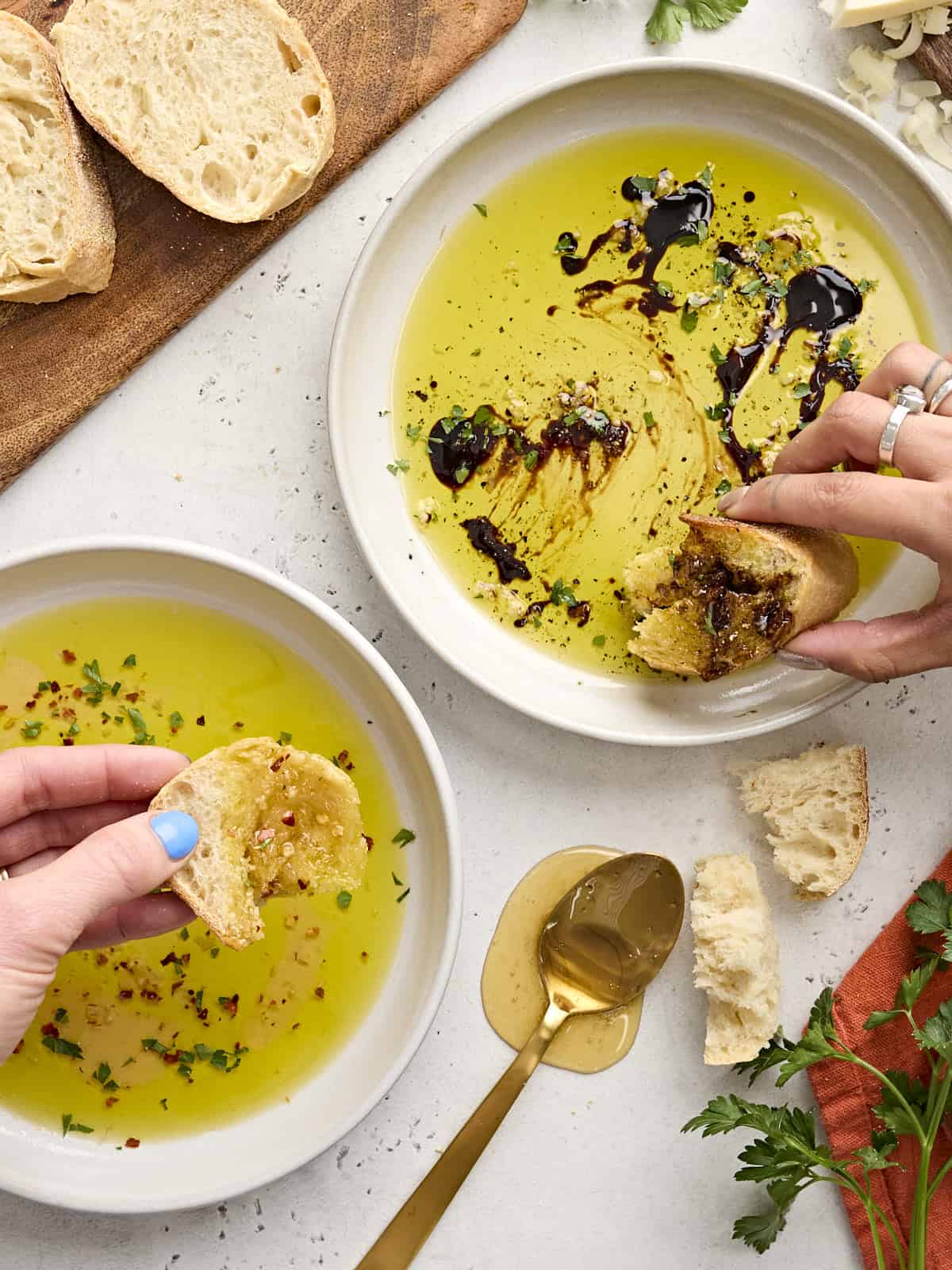 Hot honey dip and balsamic dip in white bowls on a white platter with bread and a spoon. 