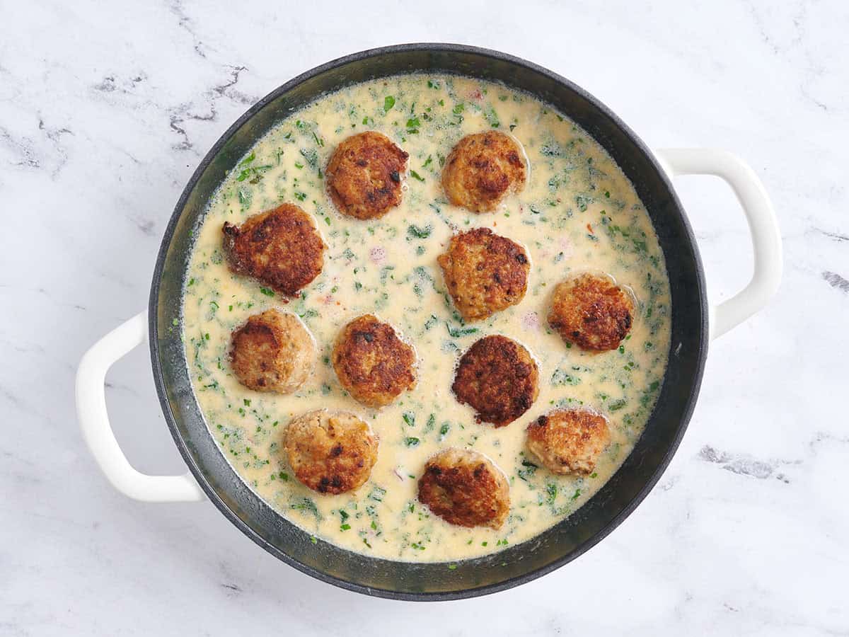 Chicken meatballs added to marry me meatballs sauce in a pan.