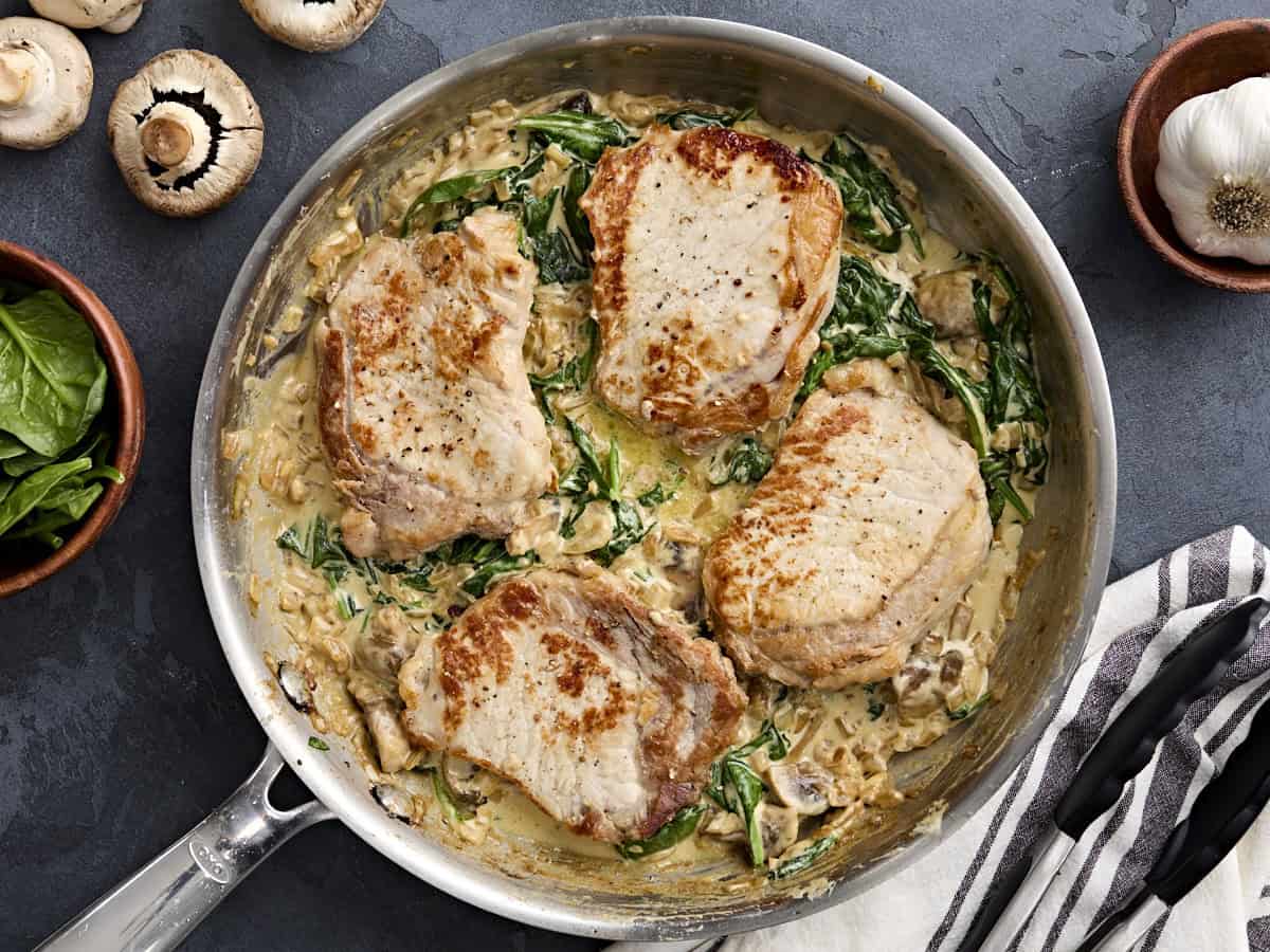 Overhead view of creamy pork chops in a skillet.