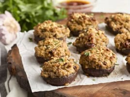 Side view of stuffed mushrooms on a wooden chopping board.