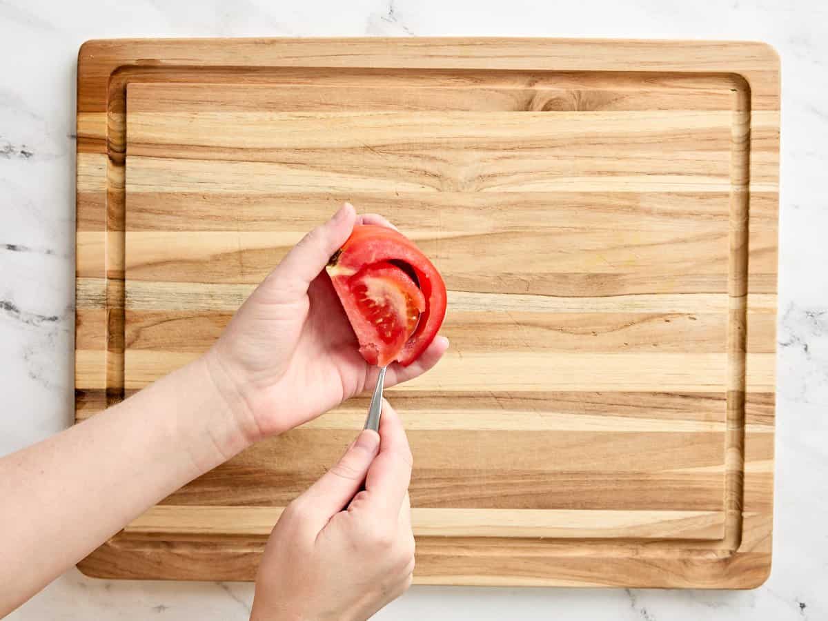 A hand deseeding a tomato.