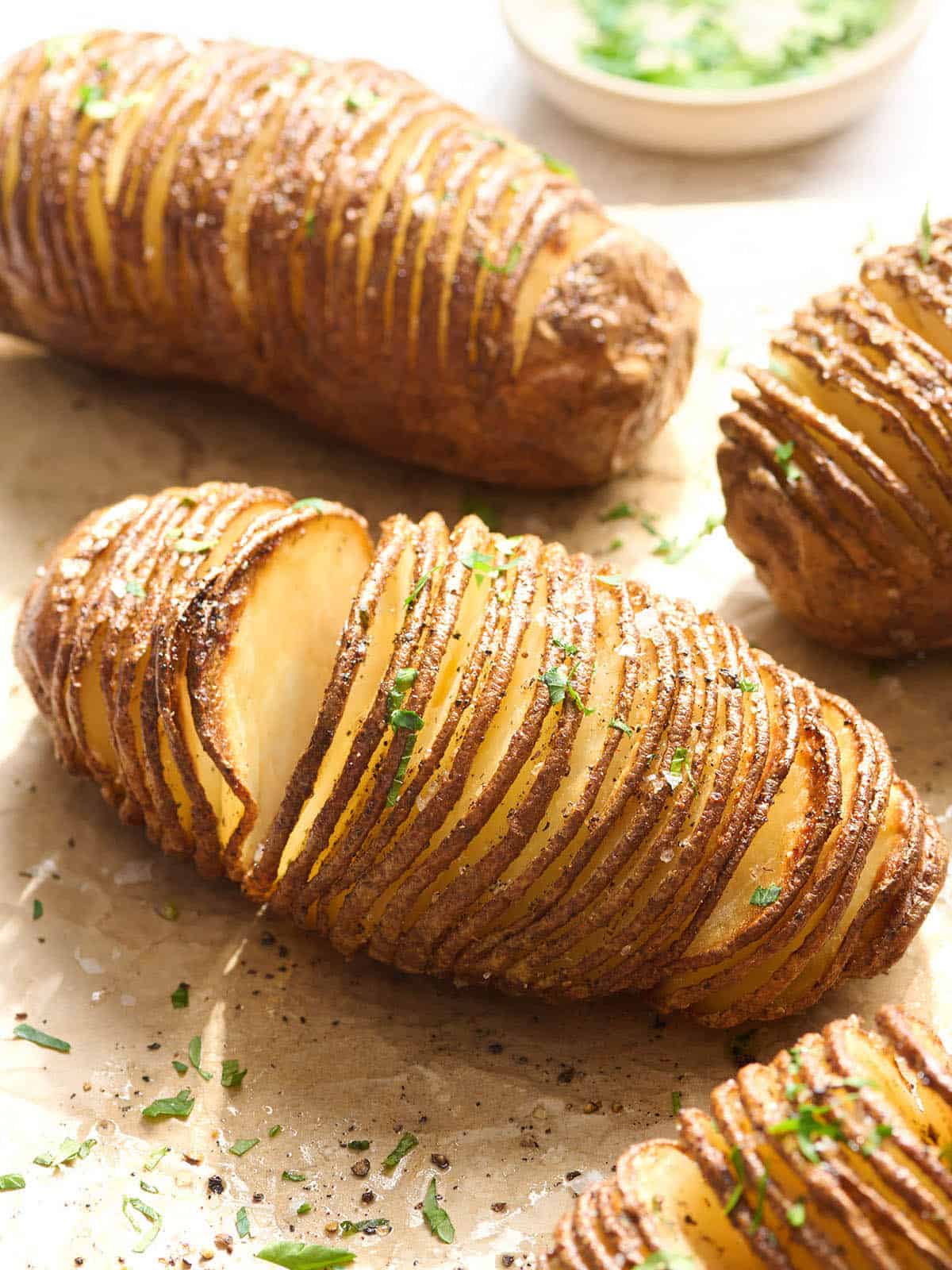 Side view of hasselback potatoes on parchment paper.