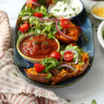 A blue platter with taco sweet potatoes, salsa, and sour cream.