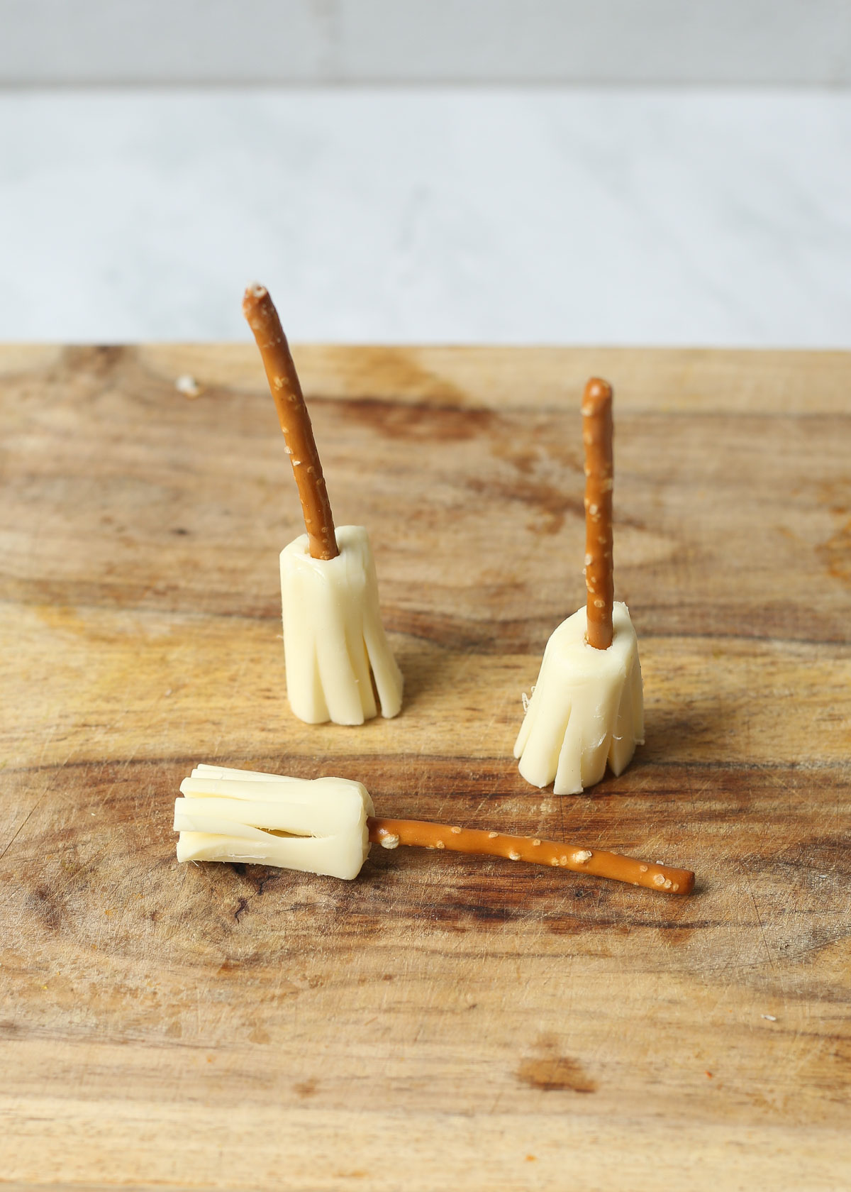 Insert the pretzel into the end of the string cheese for string cheese pretzel broomsticks.