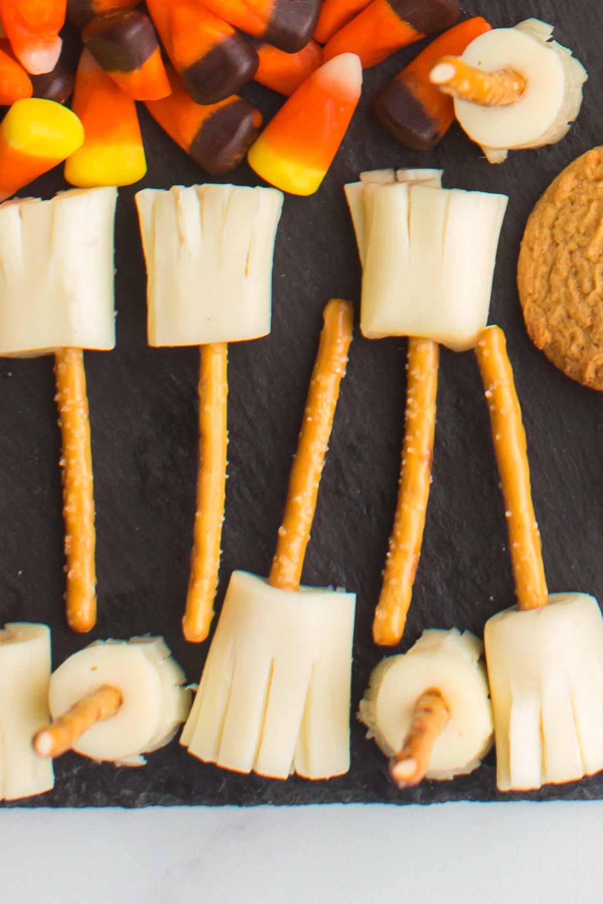 String cheese pretzel broomsticks on a slate board.