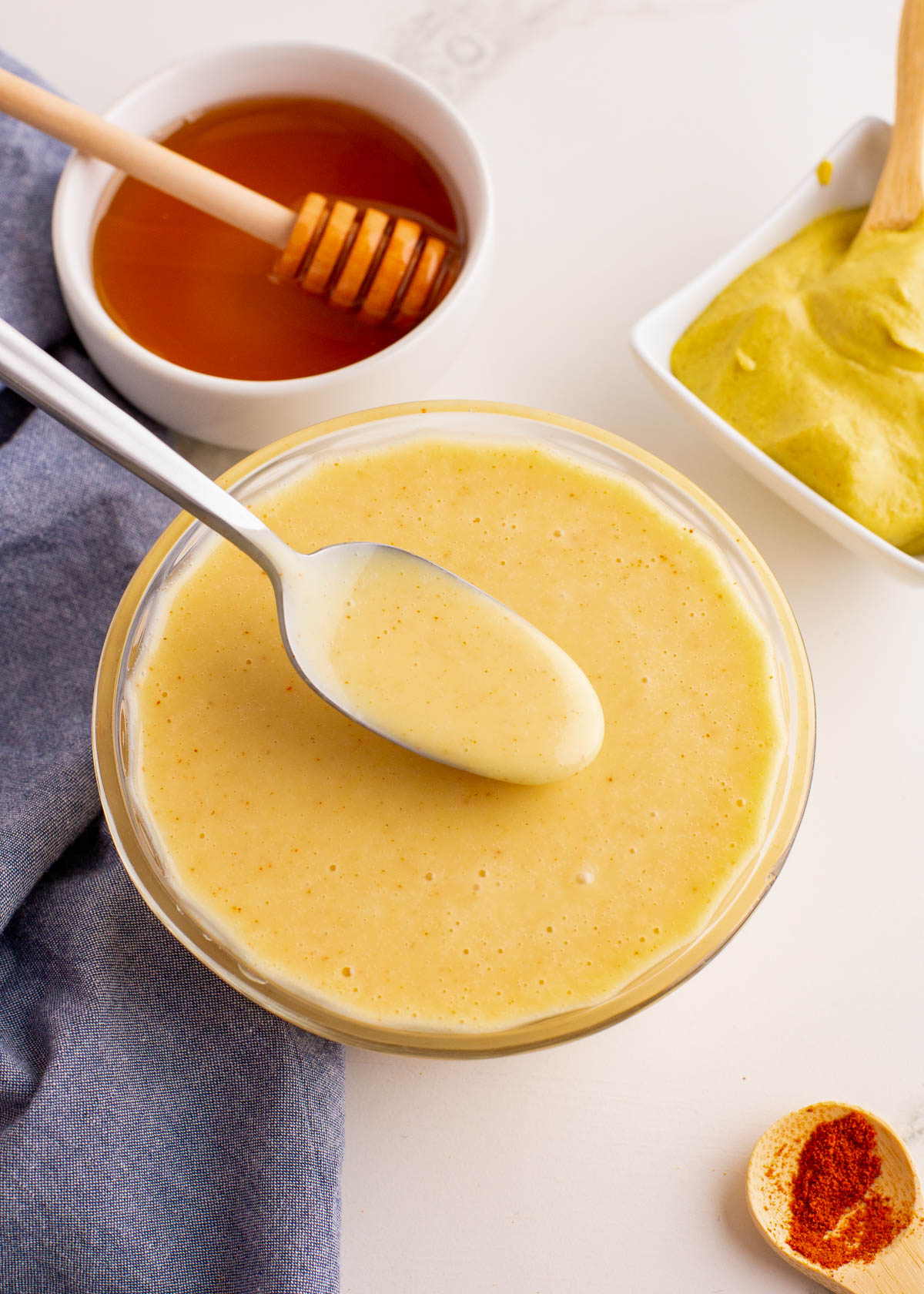 A bowl of honey dijon mustard dressing with a spoon scooping some out.