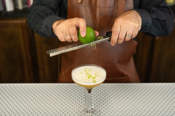 close up of zester being used to zest a lime over a cocktail