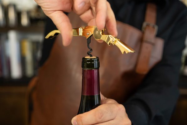 gold wine opener opening a wine bottle